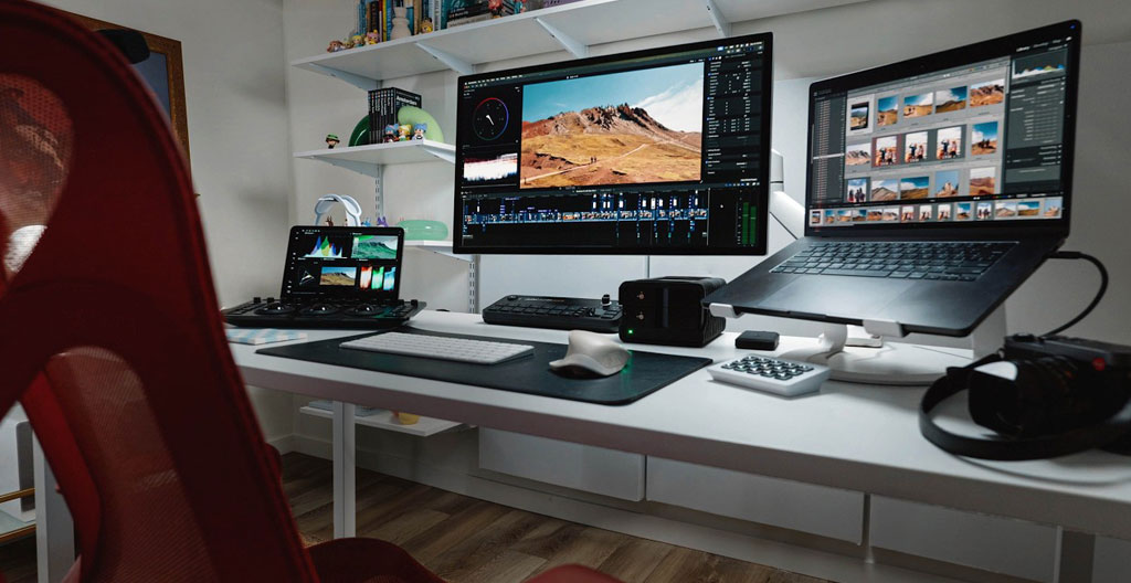Contemporary office workspace with clean desk, dual computer monitors with screens turned off, abundant natural light streaming through large windows, organised professional environment